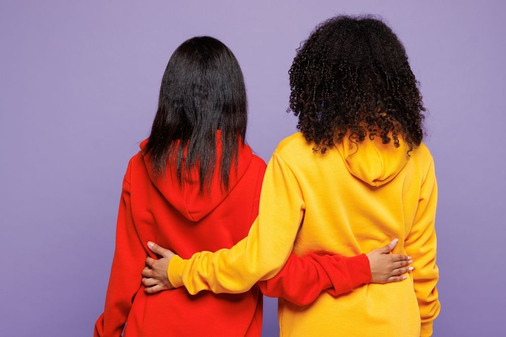 Two young sisters standing side by side with arms around each other, symbolizing resilience and the real world impact of Roblox online grooming and child safety risks