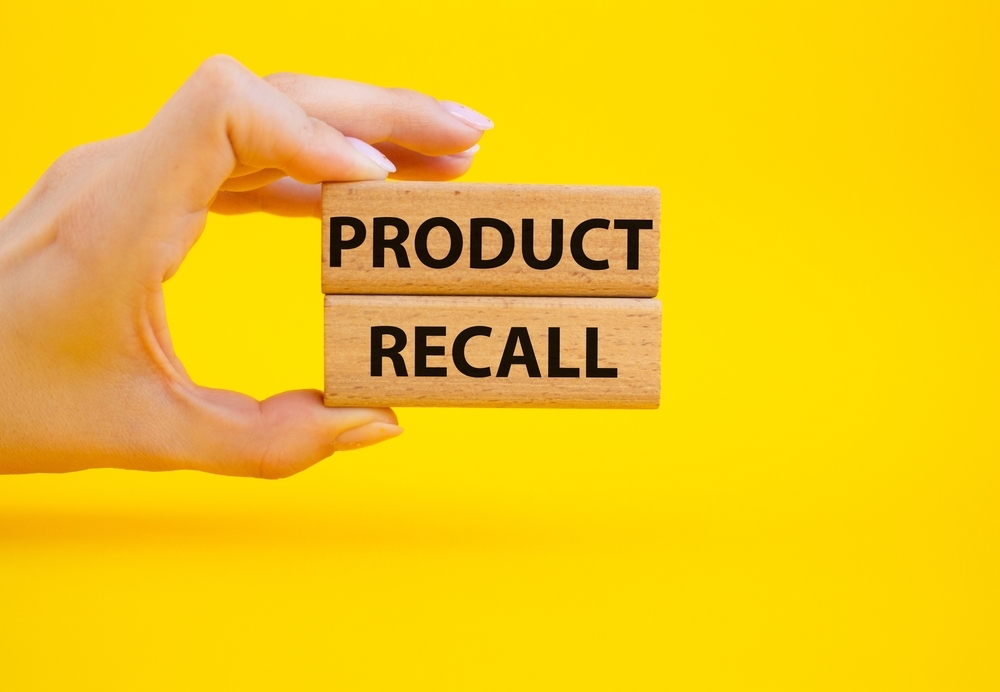 Image A hand holding wooden blocks that read "PRODUCT RECALL" against a yellow background, illustrating the Arrow International Recalls for Arrow FiberOptix and UltraFlex IAB Catheter Kits.
