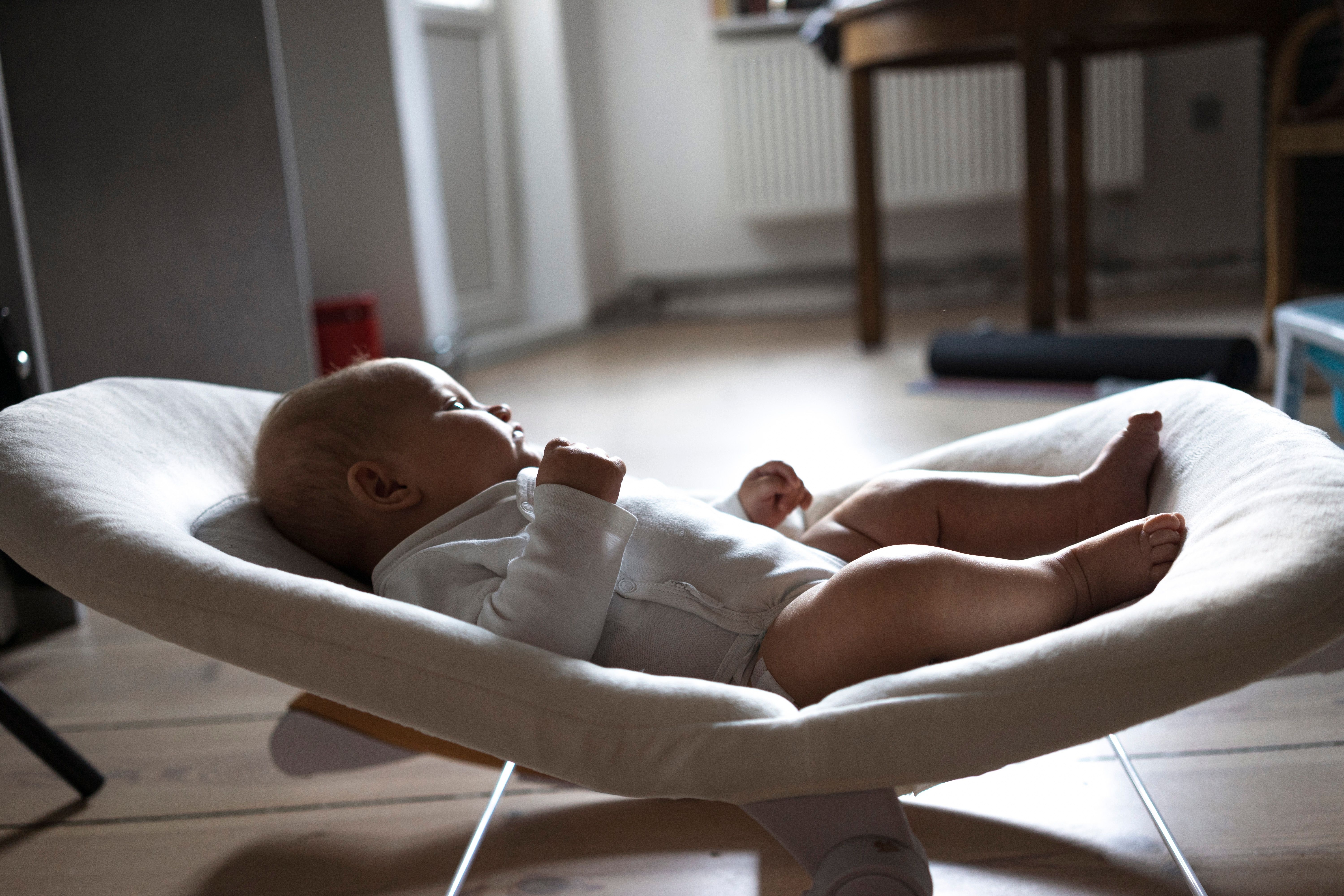 Image Infant lying in a baby lounger on a living room floor