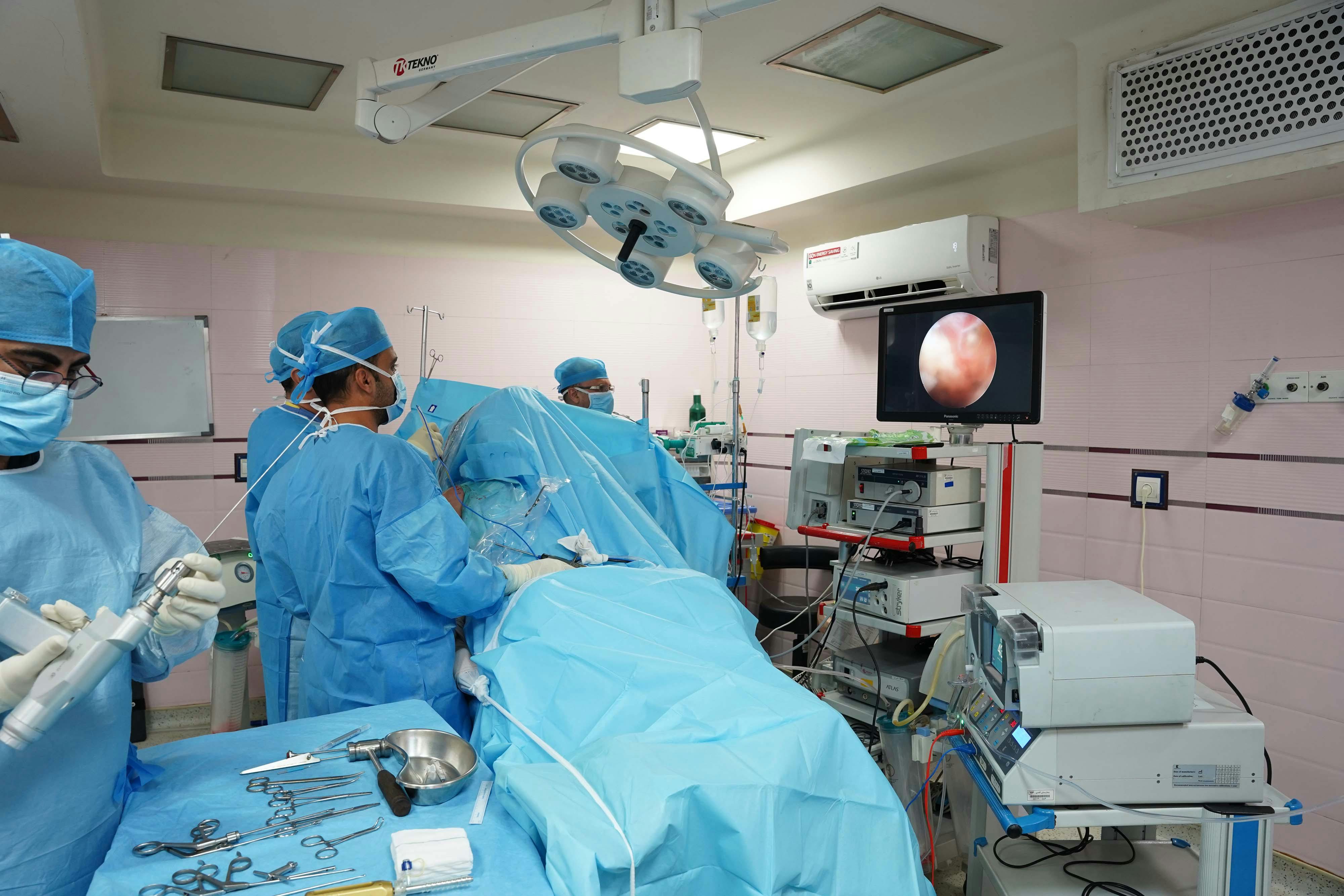 Hospital surgical team performing a procedure with endoscopic imaging equipment, illustrating medical device use and infection risk concerns