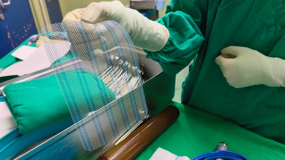 Image Surgeon holding surgical mesh used in breast procedures during an operating room setup