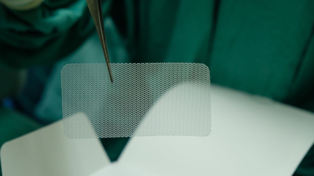 Surgical mesh material held with medical tool during procedure representing breast mesh complications and lawsuits
