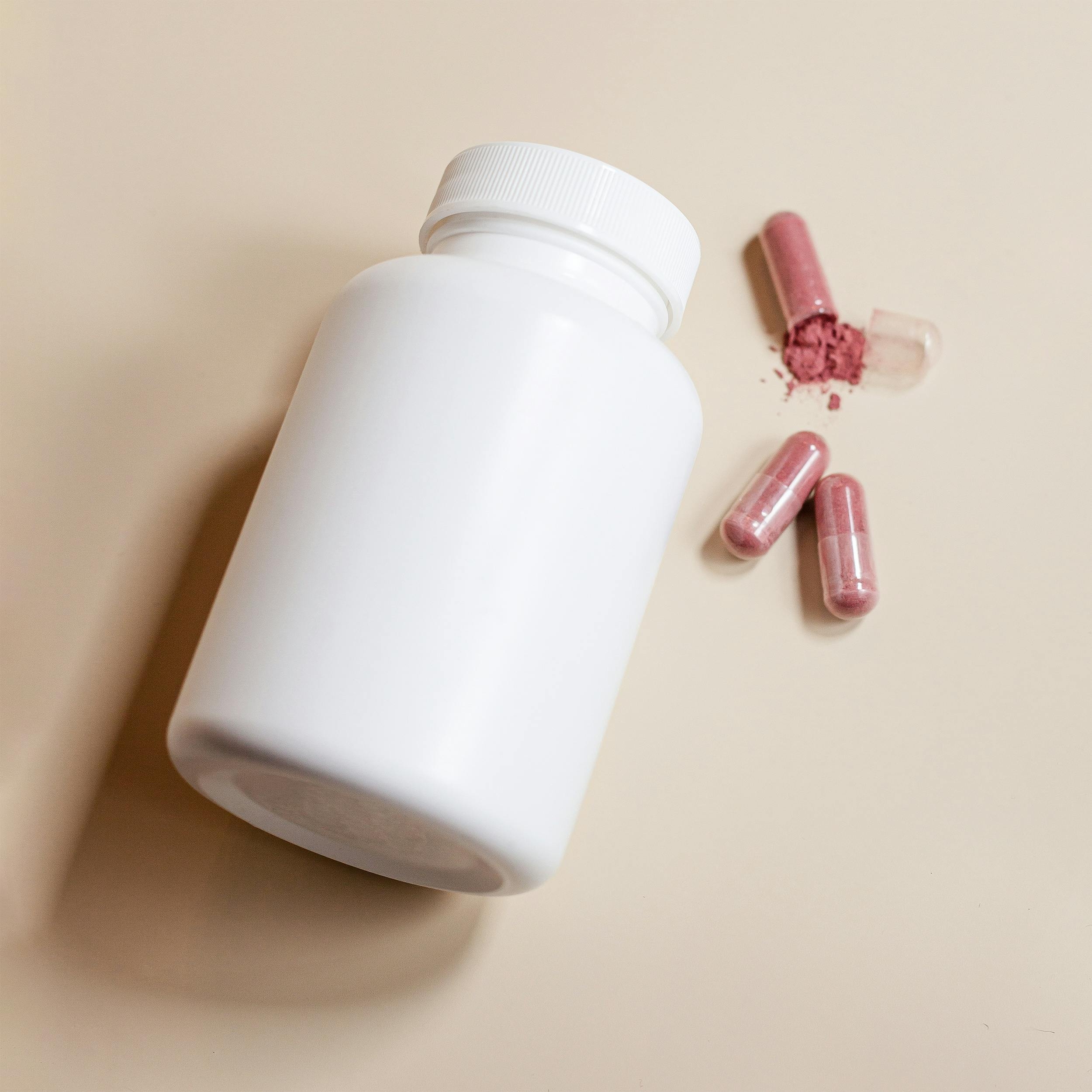 Image White supplement bottle with pink capsules, representing the iron supplement recall and child poisoning risks for families.