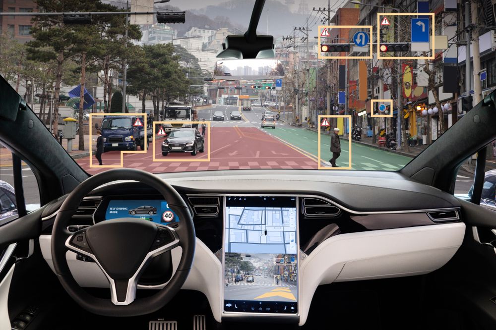 Interior of a self-driving vehicle identifying road hazards and pedestrians, illustrating Tesla Autopilot detection systems in use.
