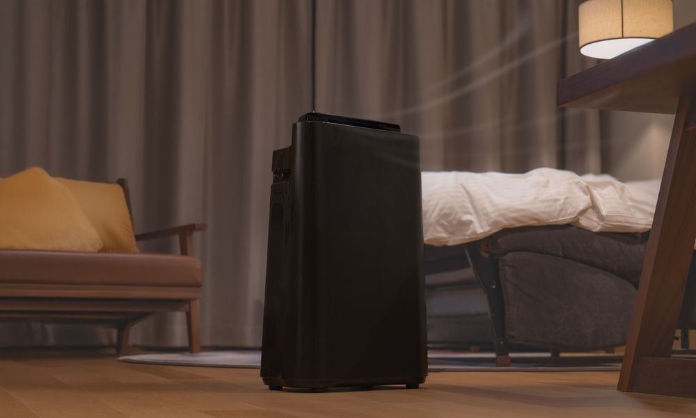 Air purifier glowing softly in a dark bedroom, symbolizing hidden fire hazards behind the Aroeve air purifier recall