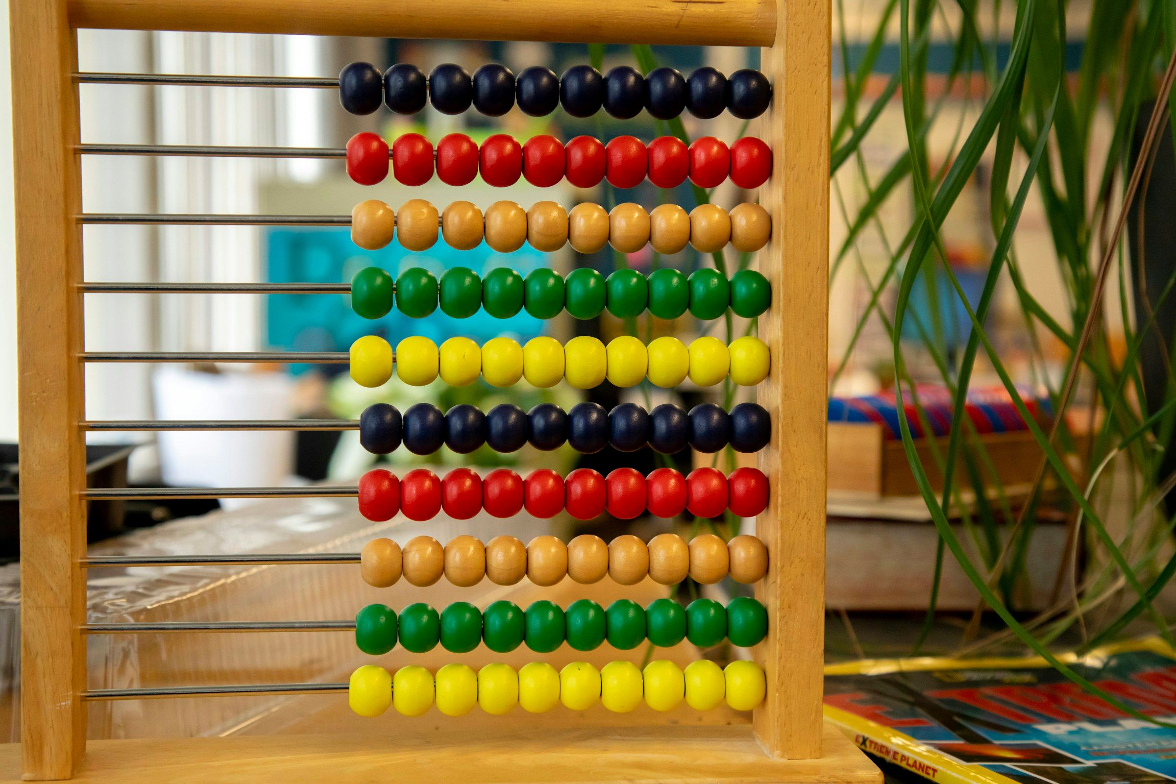 A wooden bead frame with rows of coloured beads on a classroom table