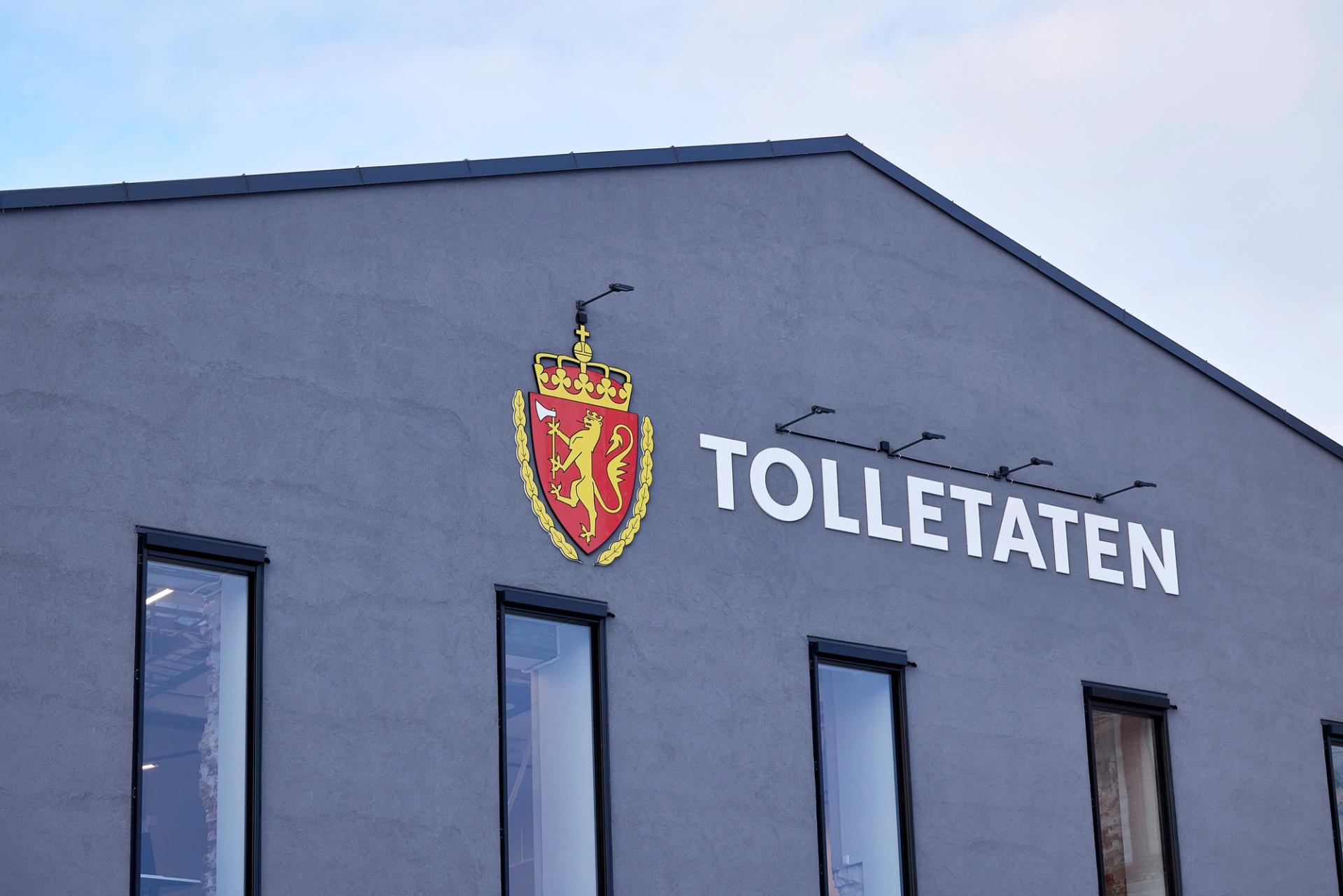 Etatsemblemet til Tolletaten på utsiden av en grå bygning