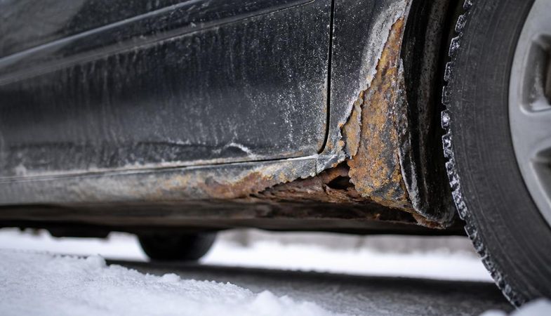 Rust corrosion along a car rocker panel and wheel arch caused by winter road salt