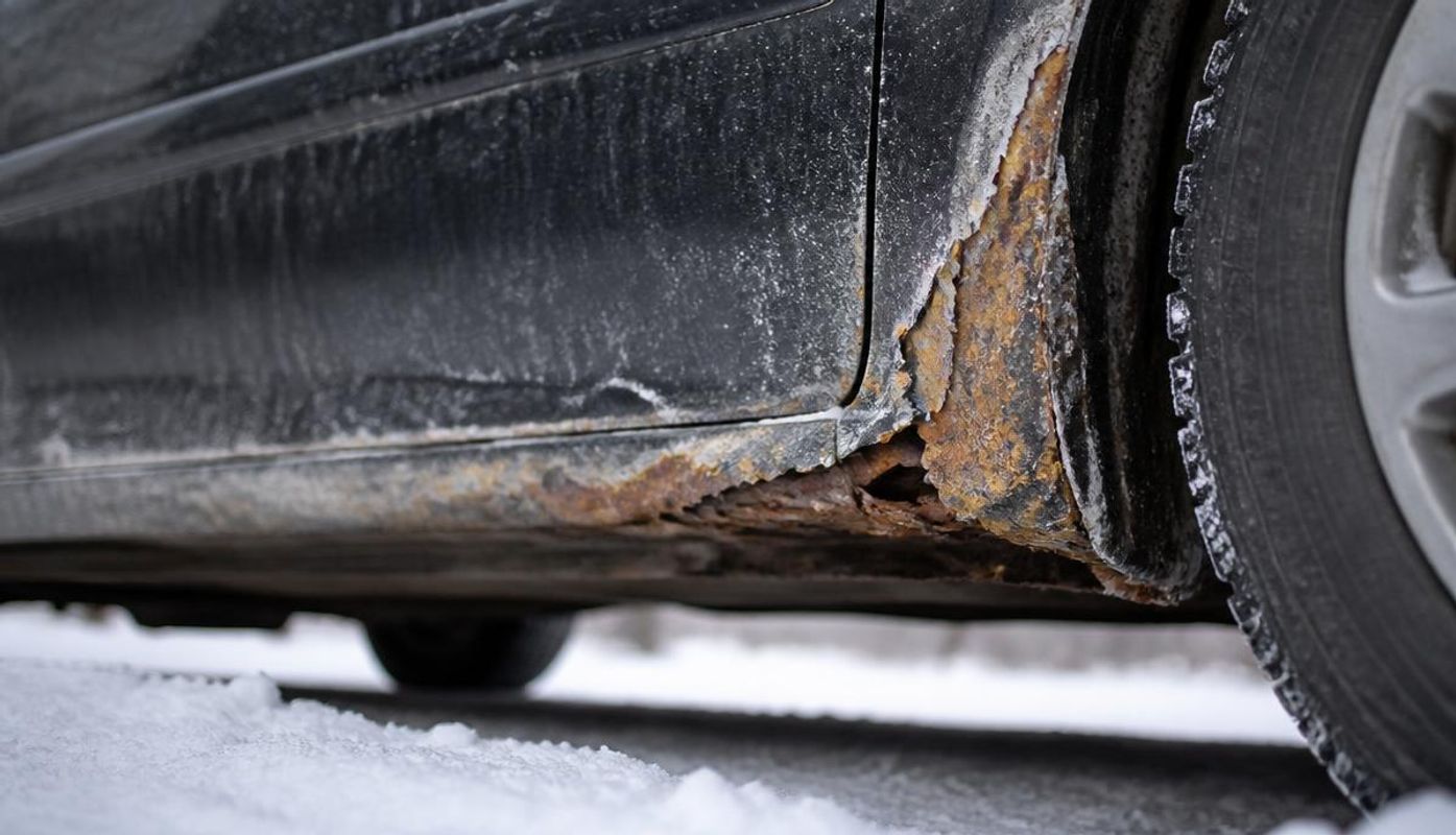 Rust corrosion along a car rocker panel and wheel arch caused by winter road salt