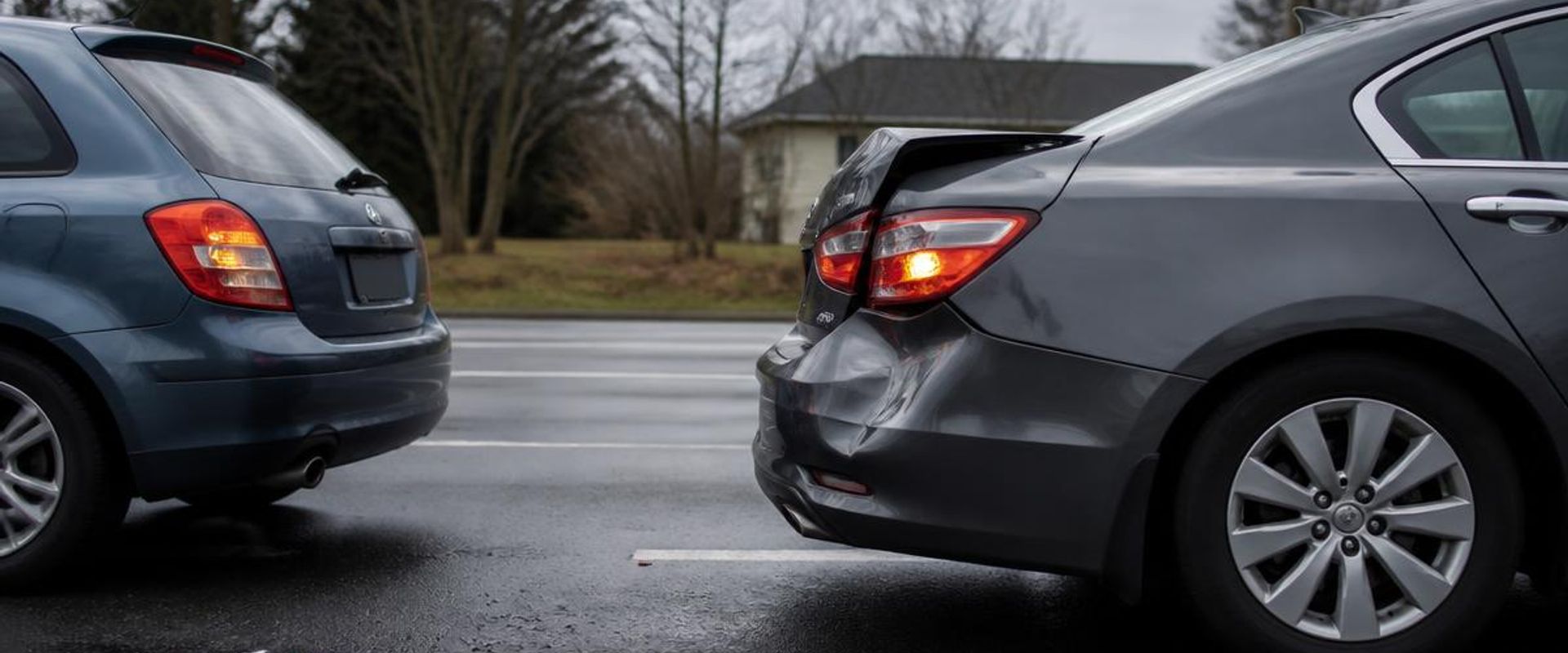 Rear-end collision aftermath on a suburban road with a crumpled bumper and hazard lights on