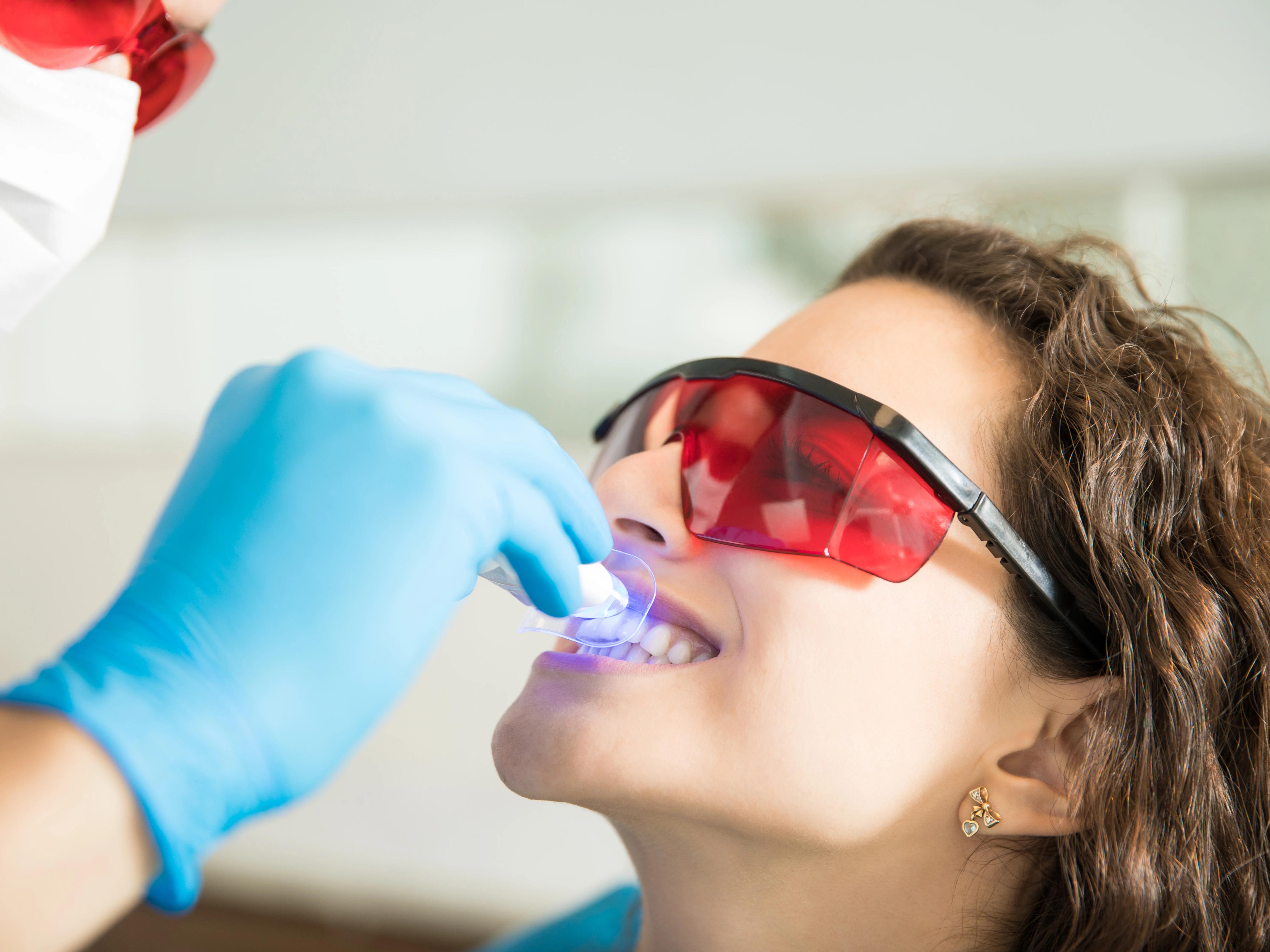 Closeup young woman having her teeth whitened with ultraviolet light
