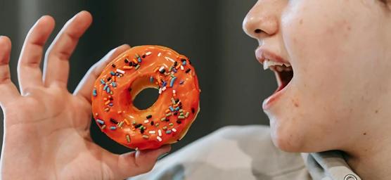 Girl eating a doughnut representing the impact of sugar on dental health