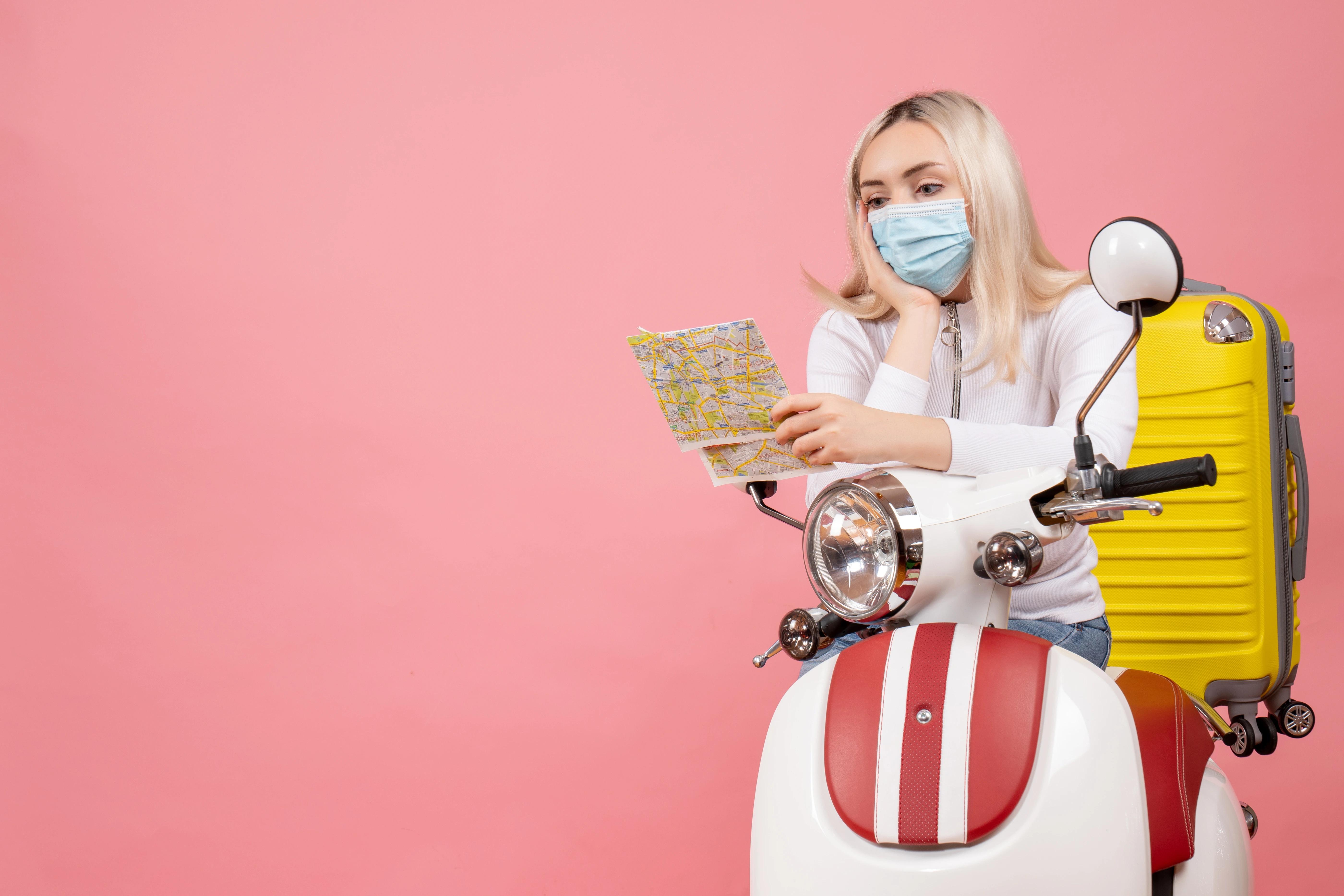 Woman on motorcycle with medical mask and map