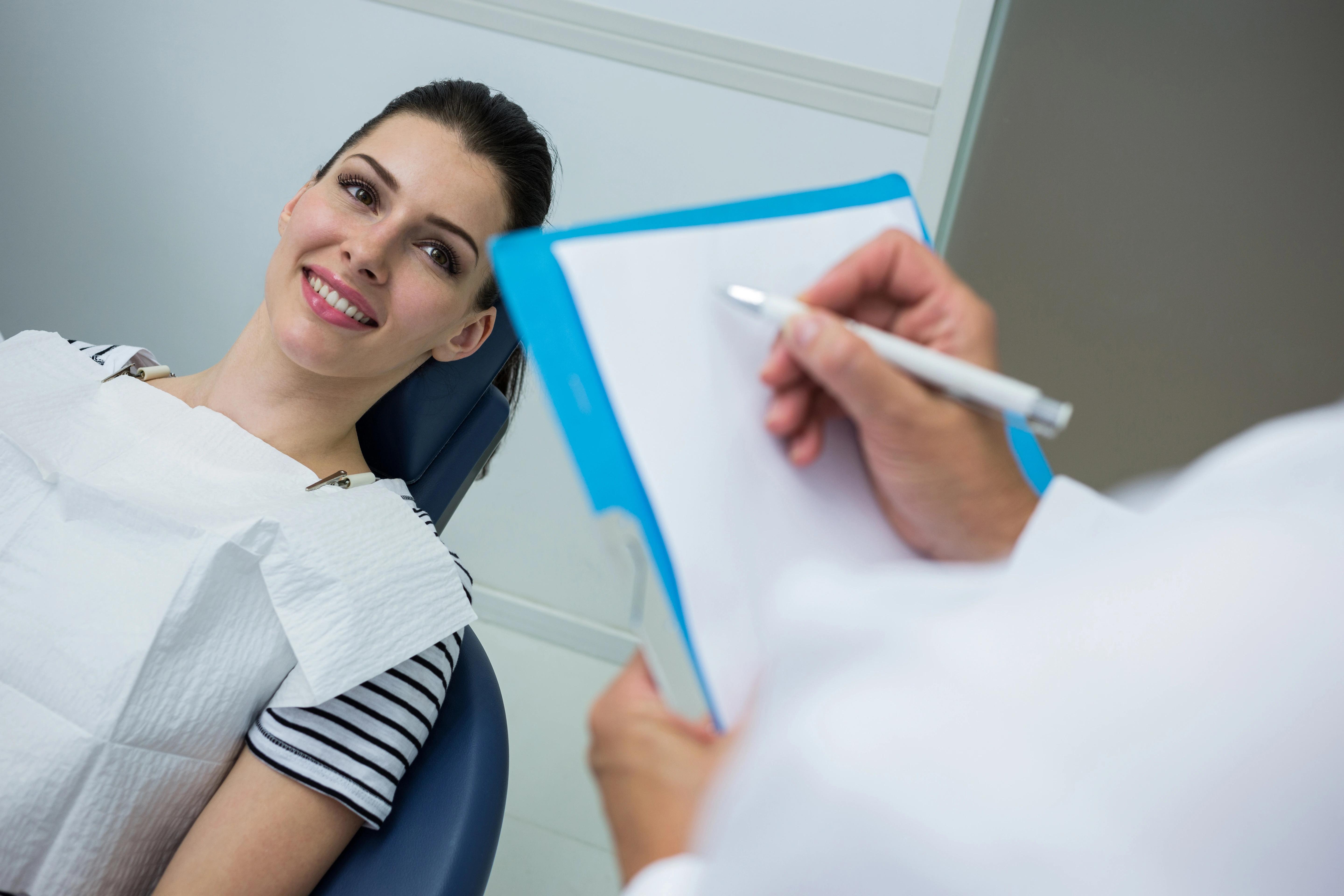 Dentist writing while patient sitting down