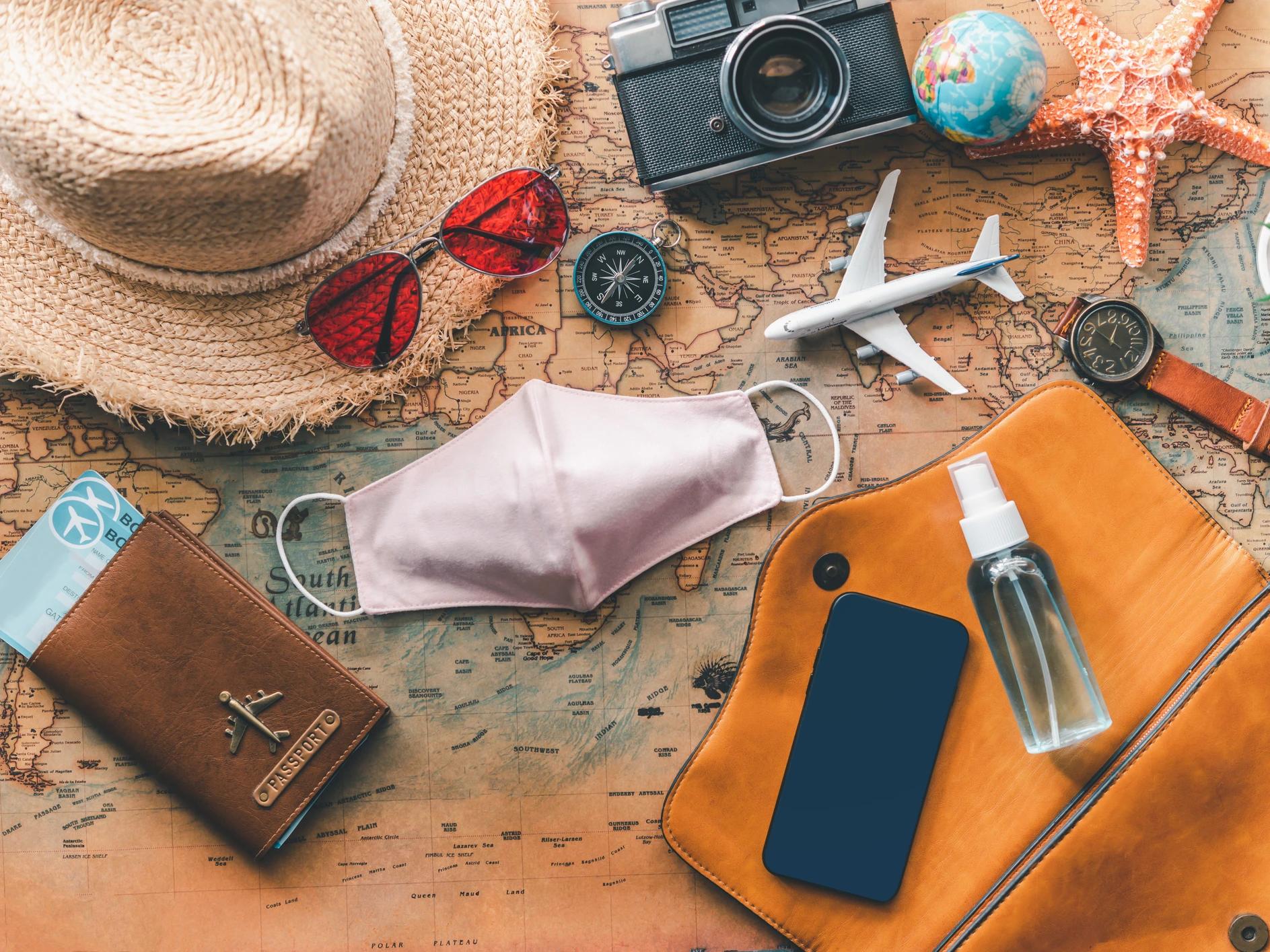 Map with travel items, passport, and dental mask.