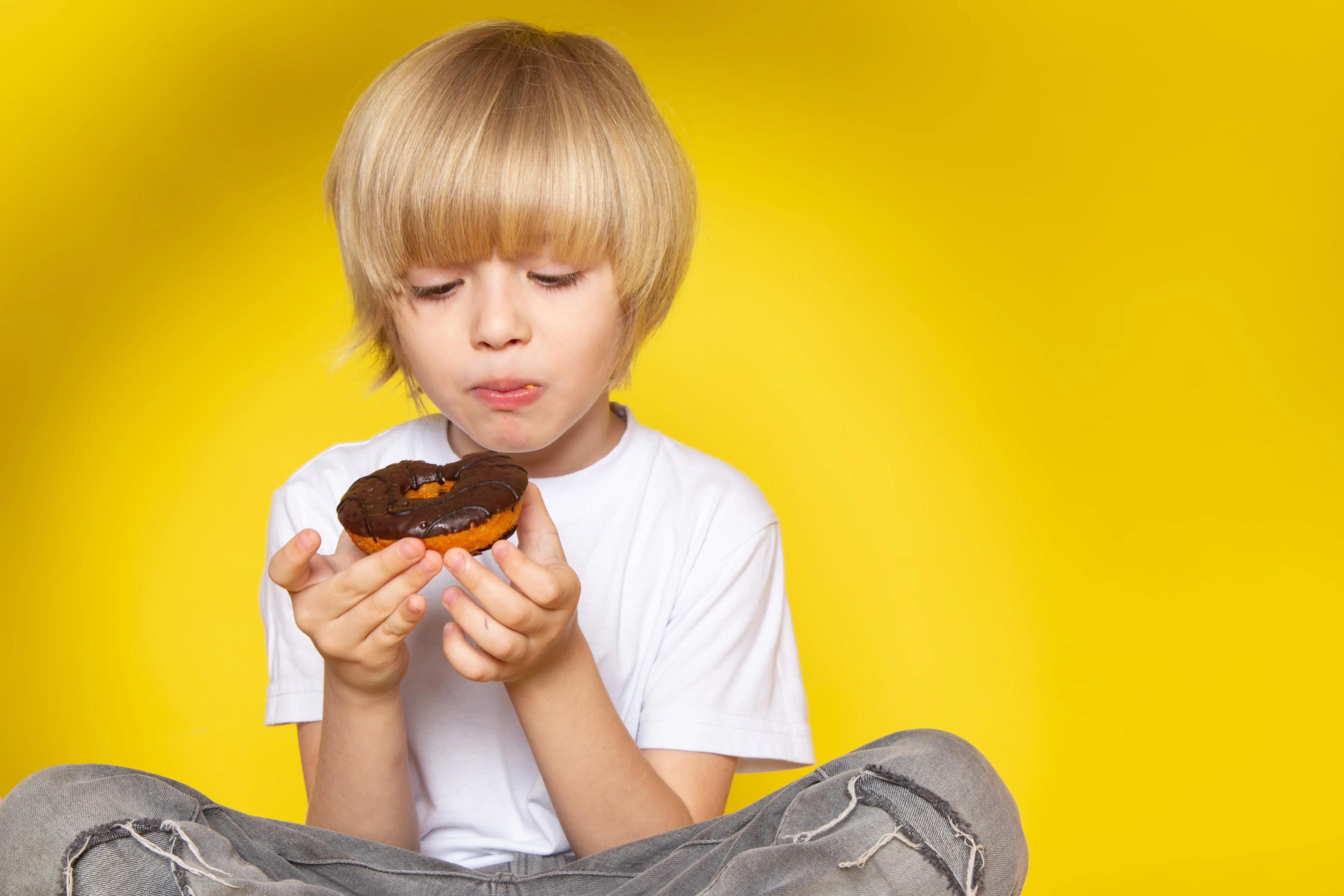 Child eating a doughnut representing the impact of sugar on dental health