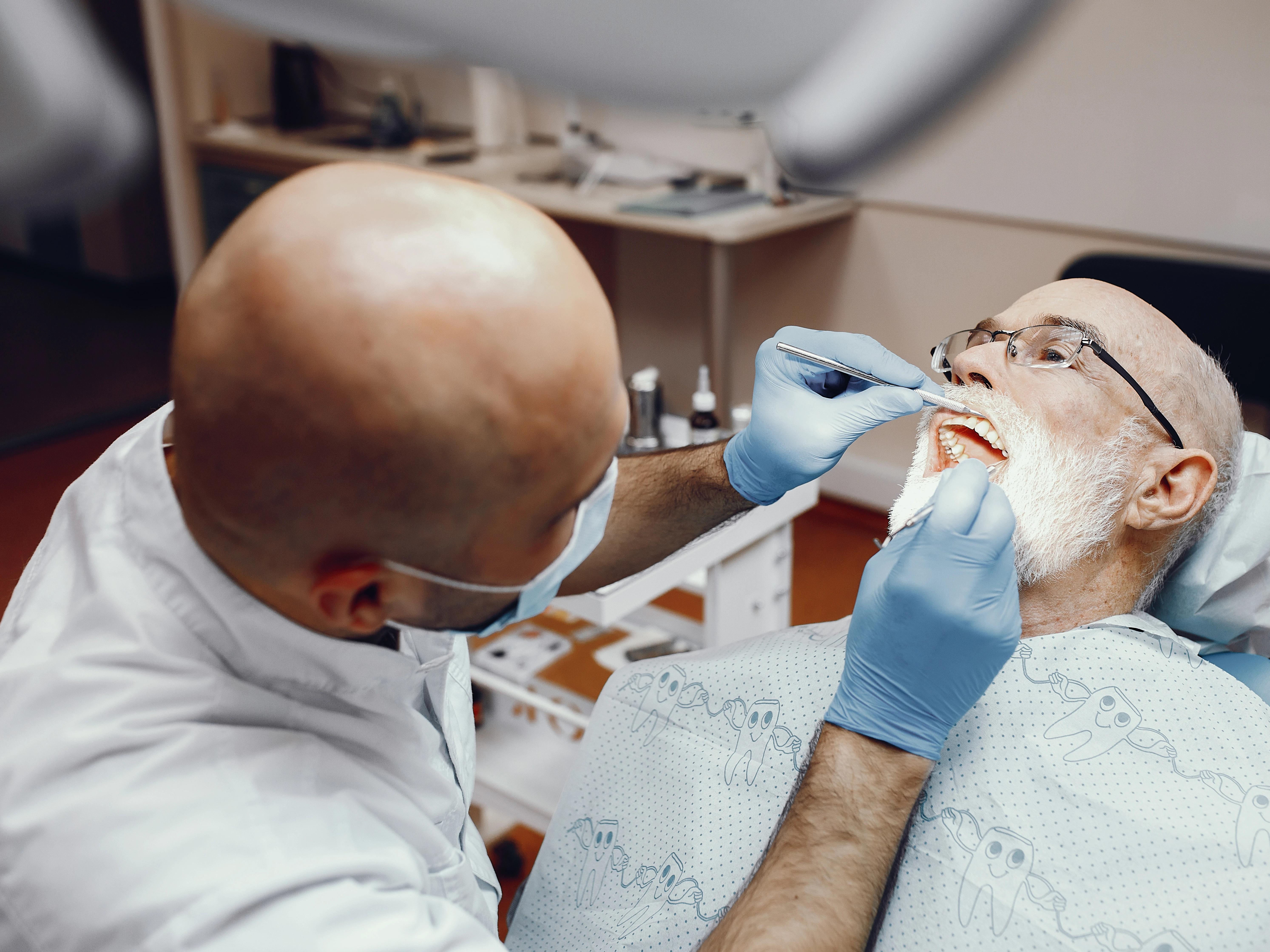 old man sitting dentist's office desktop doing dental bone graft image