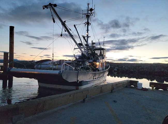 A fishing vessel docked at a coastal B.C. wharf at dusk.