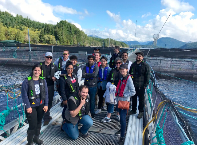 A group of young people on a net-pen walkway at a salmon farm in coastal British Columbia.