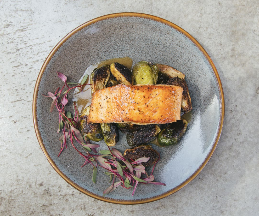 Pan-seared salmon fillet plated with roasted vegetables and microgreens