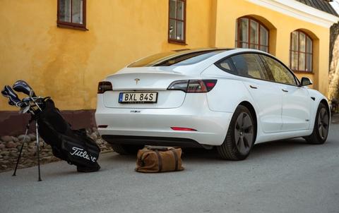 En parkerad Tesla Model 3 med golfprodukter från Titleist
