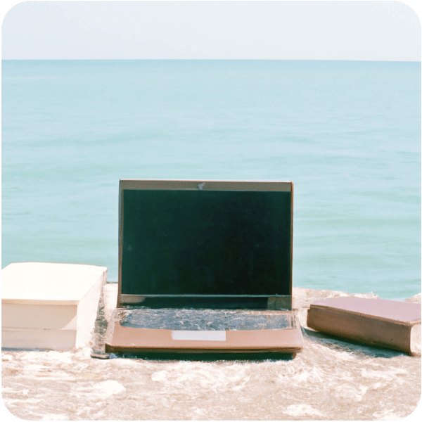 Books and a laptop a few metres from the sparkling italian sea seen through a summer haze