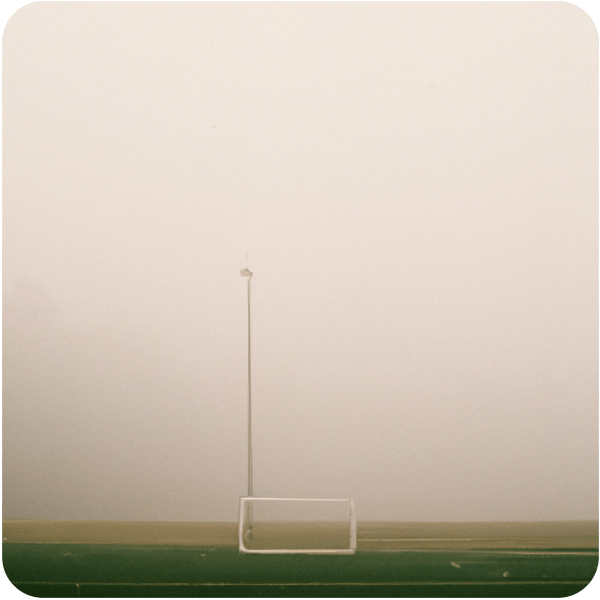 A soccer field barely visible through thick heavy fog, 35mm