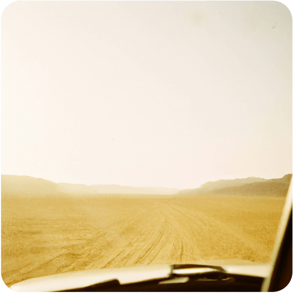 A fond memory of vintage car driving into the horizon in a vast, tranquil desert in Jordan, coated in golden light