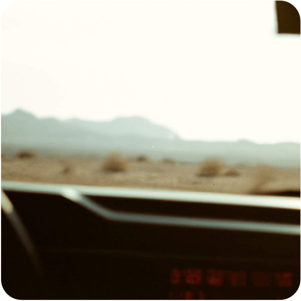 Zoomed in car dashboard with the hazy backdrop of a still desert seen through the window 