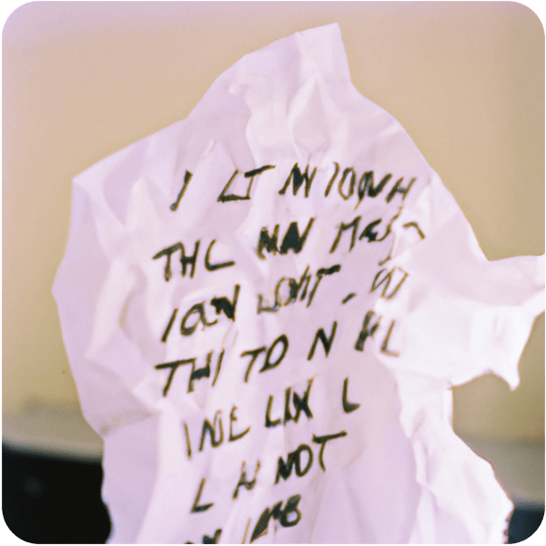 A crumpled piece of paper with song lyrics crossed out, 35mm