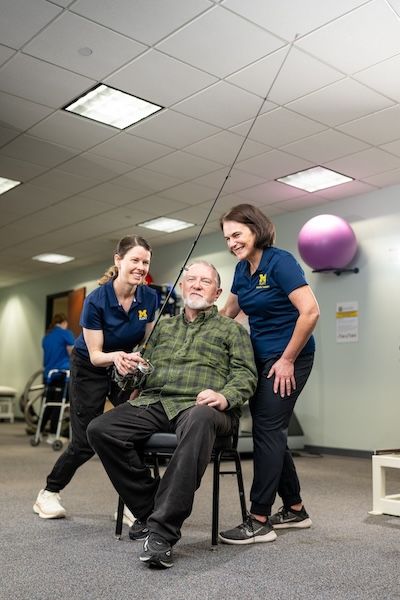 A professor and student help a patient use a fishing pole