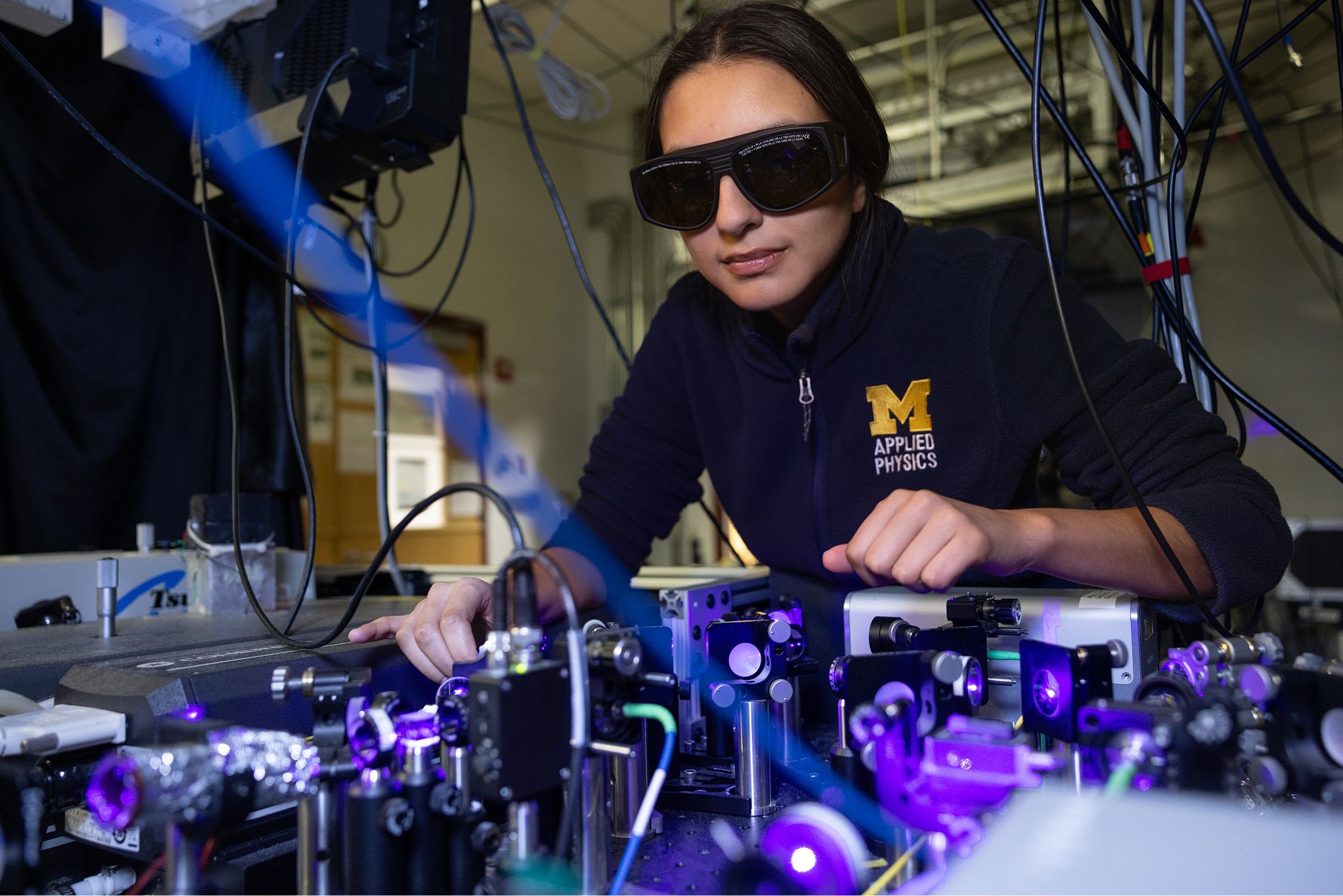 A person wearing dark goggles and adjusting some equipment
