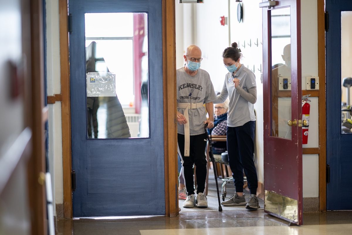 A student works with a patient who uses a cane
