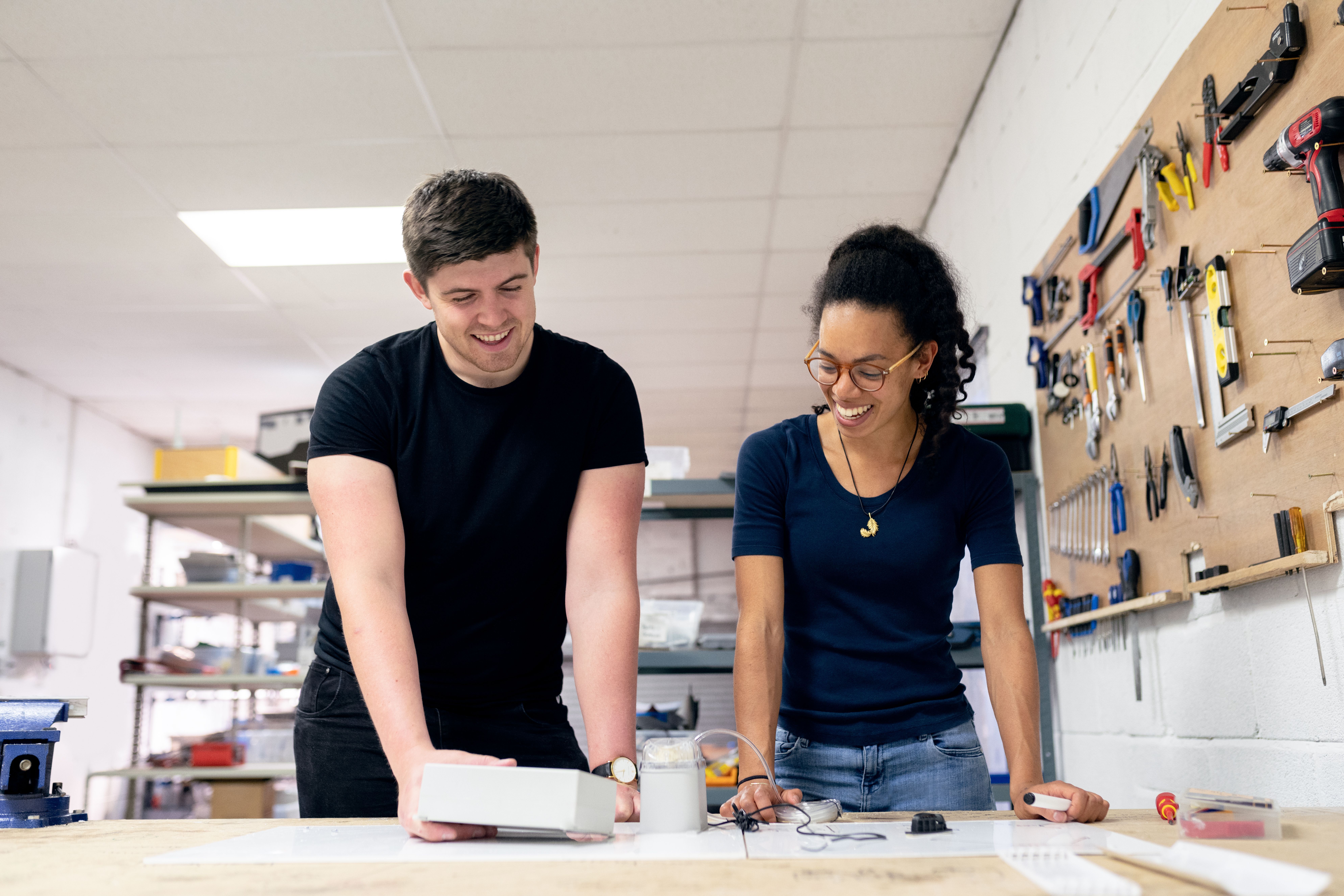 Two engineers collaborating on prototype design and assembly work at a bench in a development workshop
