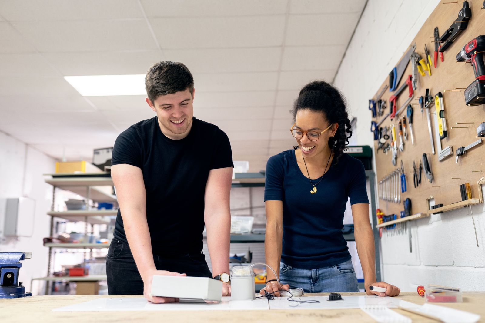 Two engineers collaborating on prototype design and assembly work at a bench in a development workshop