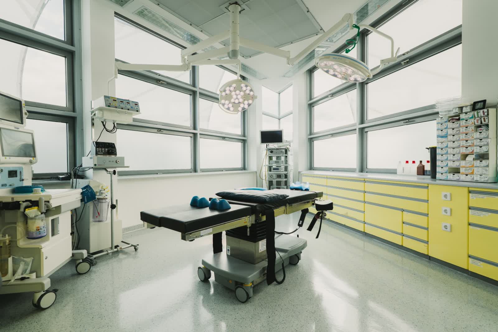 OP-Saal mit großen Fensterfronten, OP-Tisch und OP-Leuchten