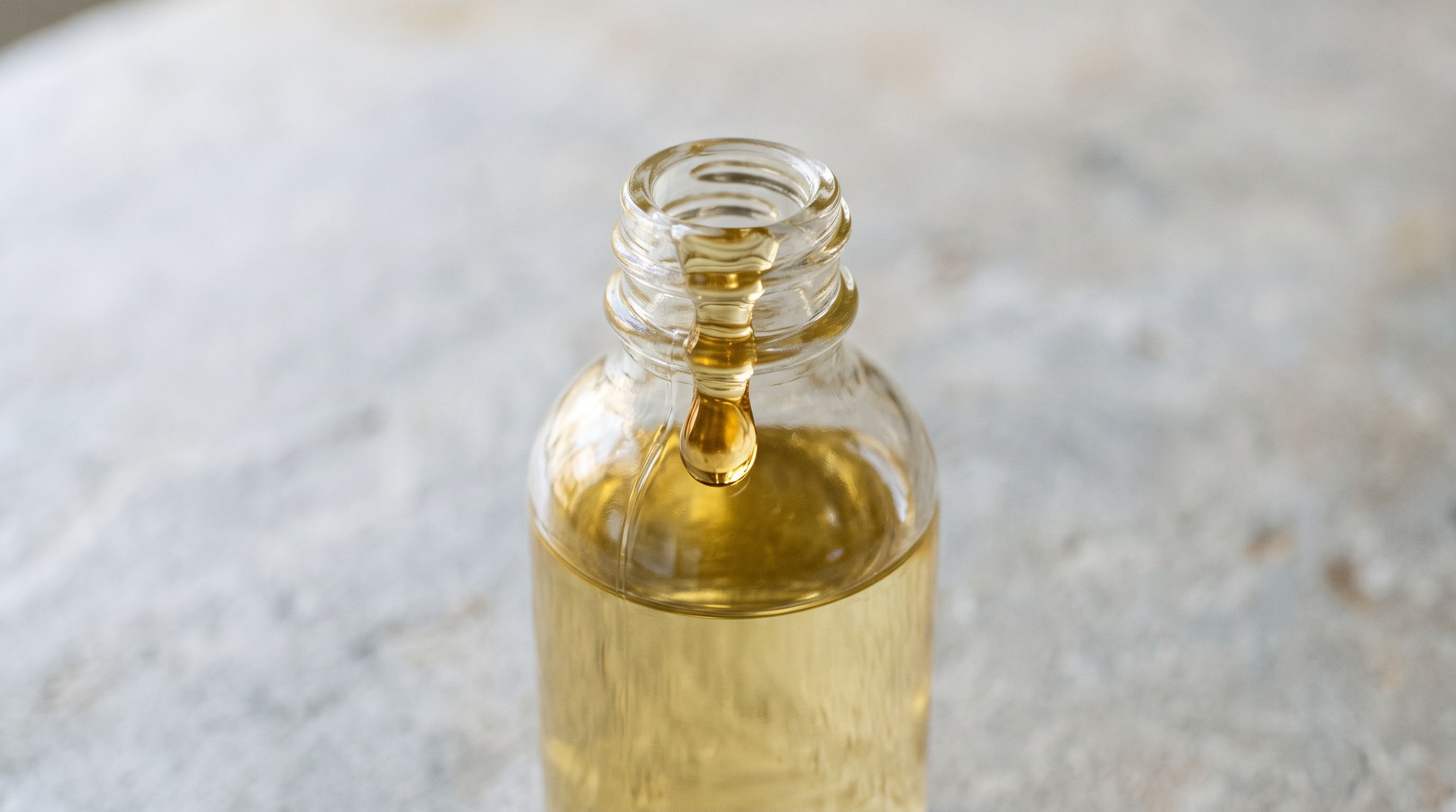 A glass bottle of castor oil on a stone surface.