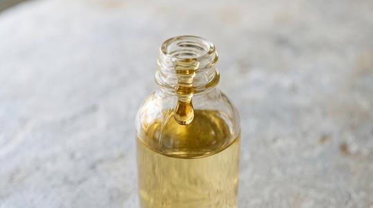 A glass bottle of castor oil on a stone surface.