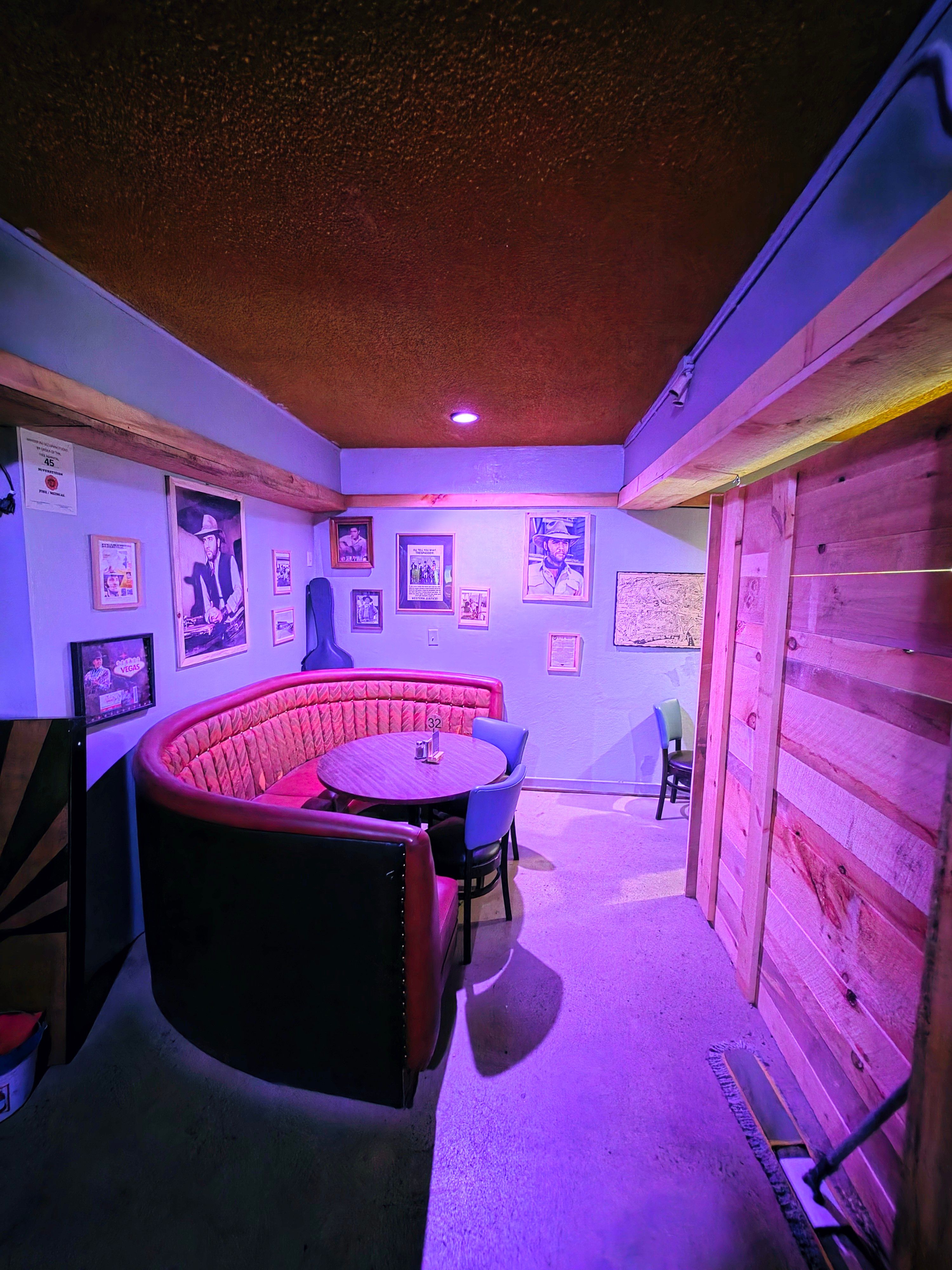 Curved red upholstered Elvis booth with a round table and framed memorabilia at Skies Bar & Grill.