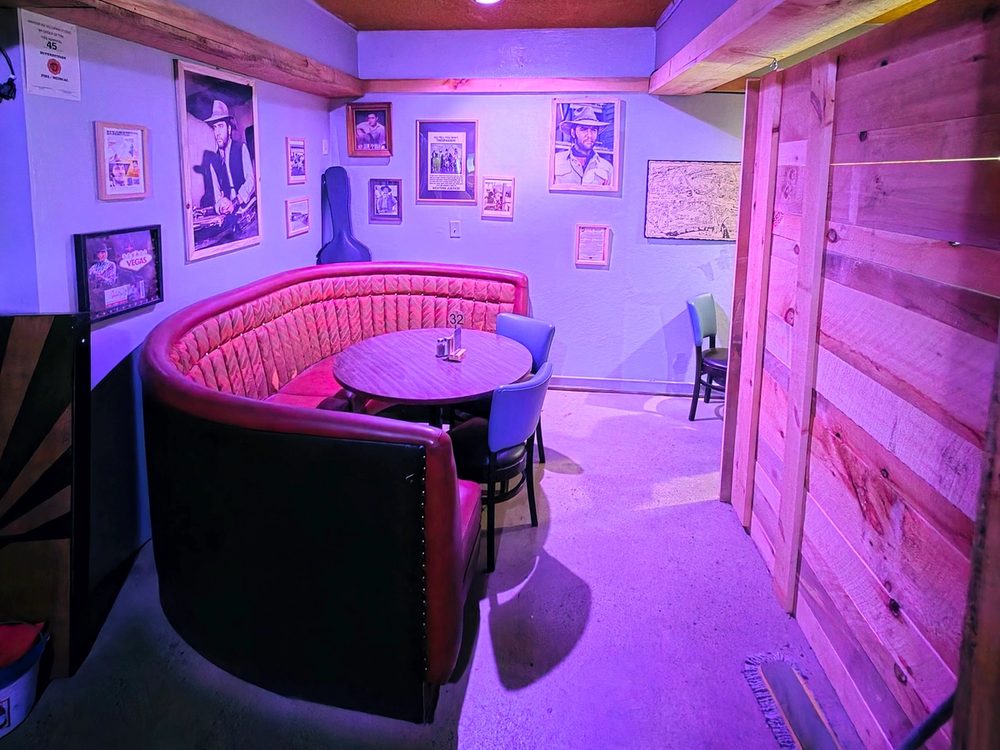 Curved red upholstered Elvis booth with a round table and framed memorabilia at Skies Bar & Grill.