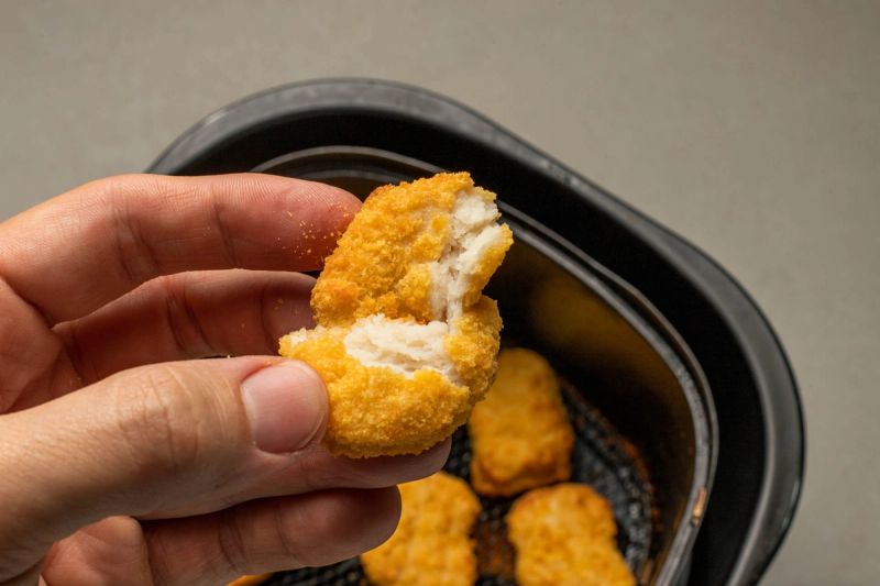 Holding a cooked torn chicken nugget
