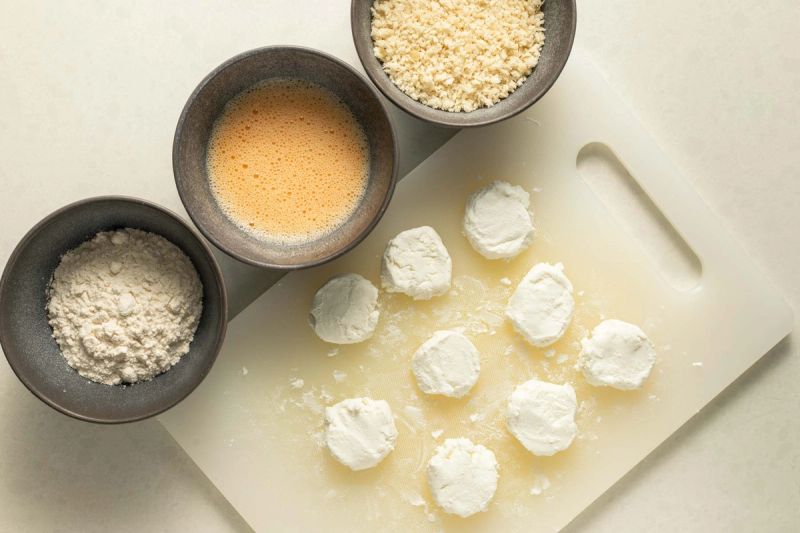 Preparing to dredge goats cheese on table