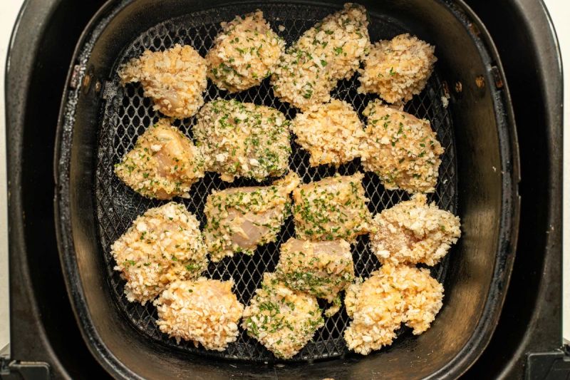 Raw breaded chicken in air fryer basket Raw breaded chicken in air fryer basket