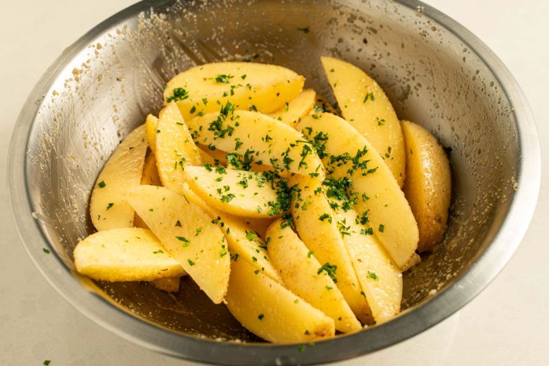 Fresh herbs on potato wedges in bowl