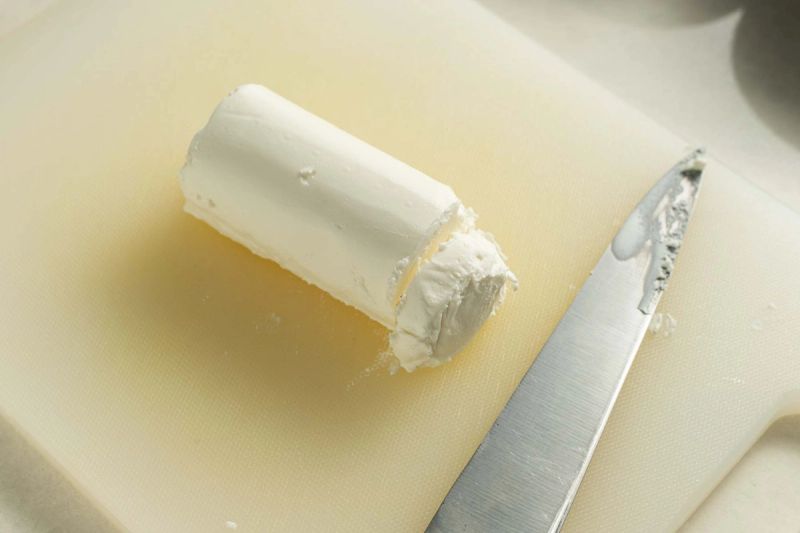 Slicing a goats cheese log on cutting board Slicing a goats cheese log on cutting board