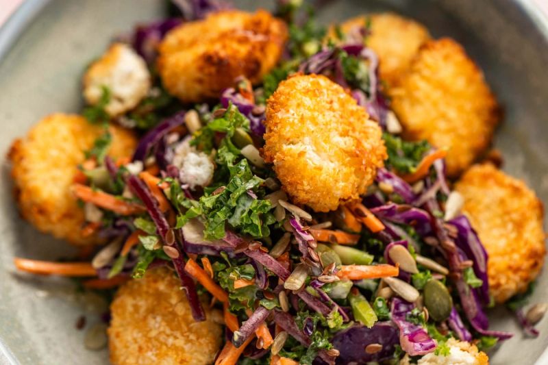 Goats cheese on top of a kale slaw salad