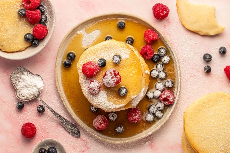 Pancakes with fresh berries, maple syrup, and icing sugar