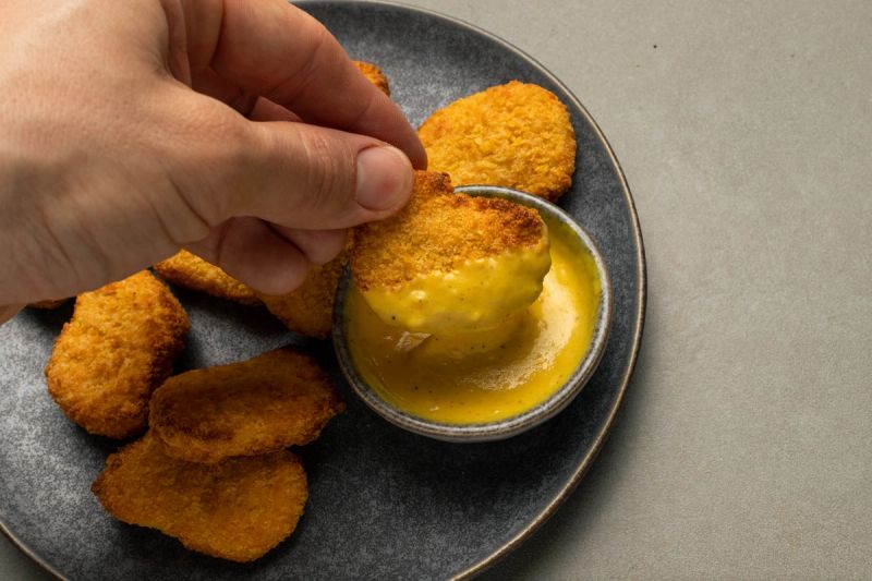 Dipping chicken nugget into honey mustard sauce