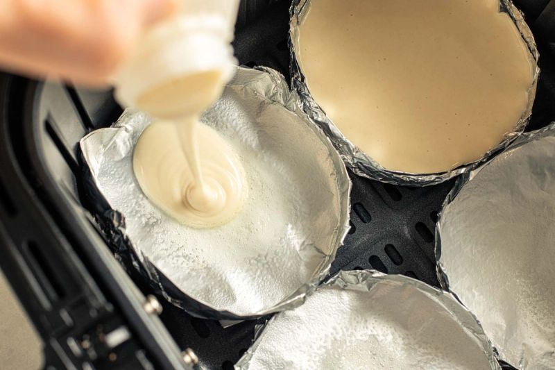 Pouring pancake batter into foil trays