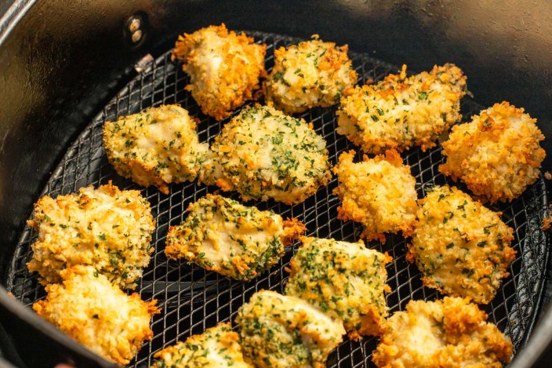 Semi cooked chicken bites in air fryer basket Semi cooked chicken bites in air fryer basket